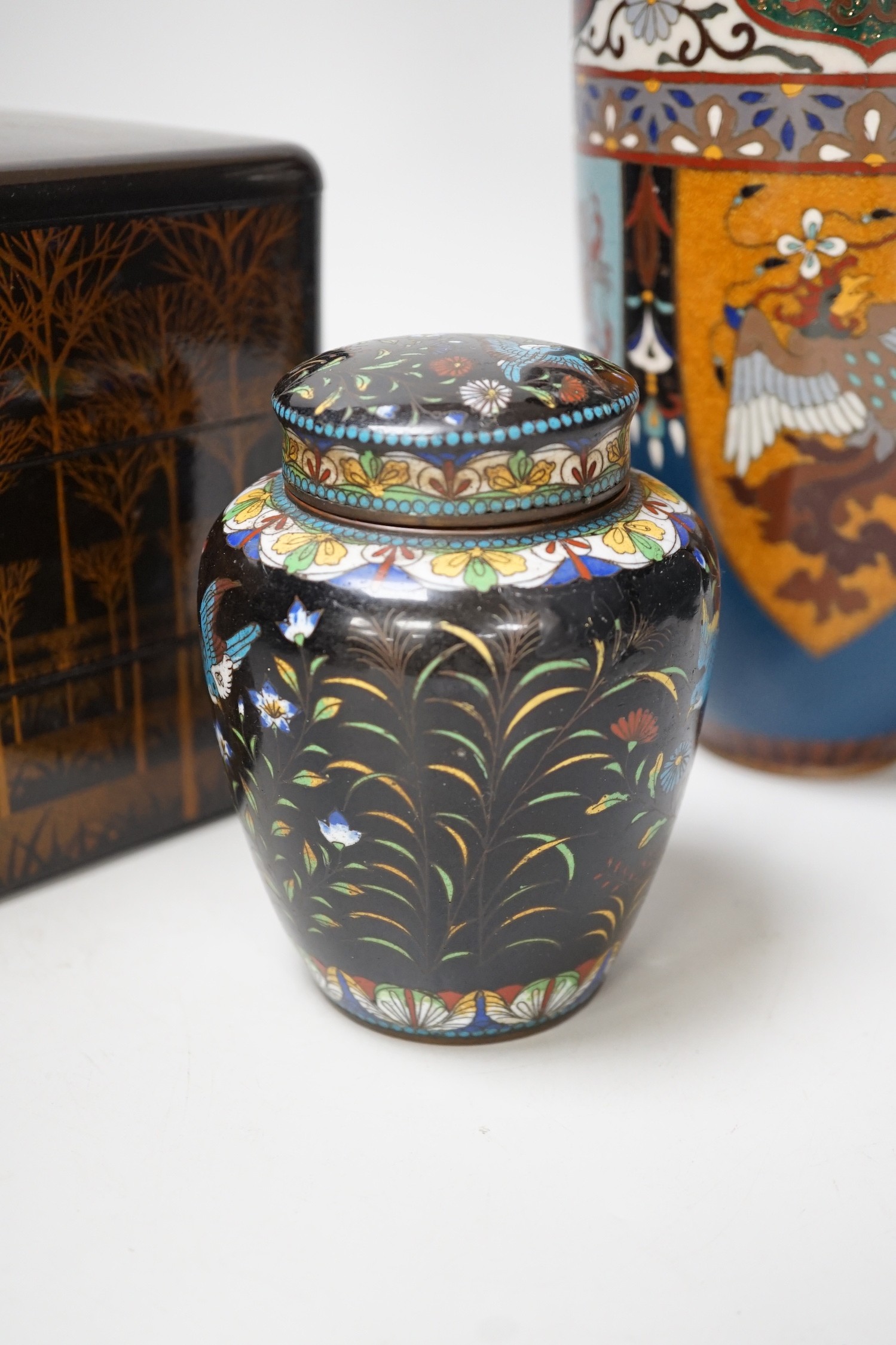 A large Japanese cloisonné enamel vase, 30.5cm high, a similar jar and cover and a Japanese lacquered tiered box with 3-4 drawers. Tree design in gold lacquer.